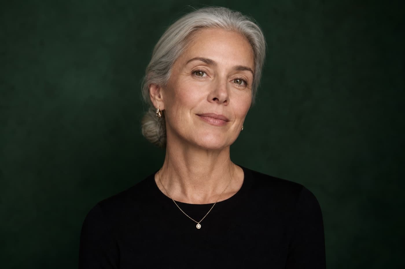 Radiant woman in a forest green studio portrait, longevity wellness
